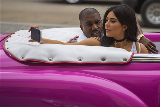 American reality-show star Kim Kardashian takes a selfie as she rides on a classic car next to her husband, rap singer Kanye West in Havana, Cuba, Wednesday, May 4, 2016. West, Kardashian and members of her reality-show-star family have become the latest celebrities to visit Havana. They visited Havanas Museum of Rum Wednesday, stepping out of a hot-pink antique American convertible as they snapped selfies and were recorded by a television crew following them around.(AP Photo/Desmond Boylan)