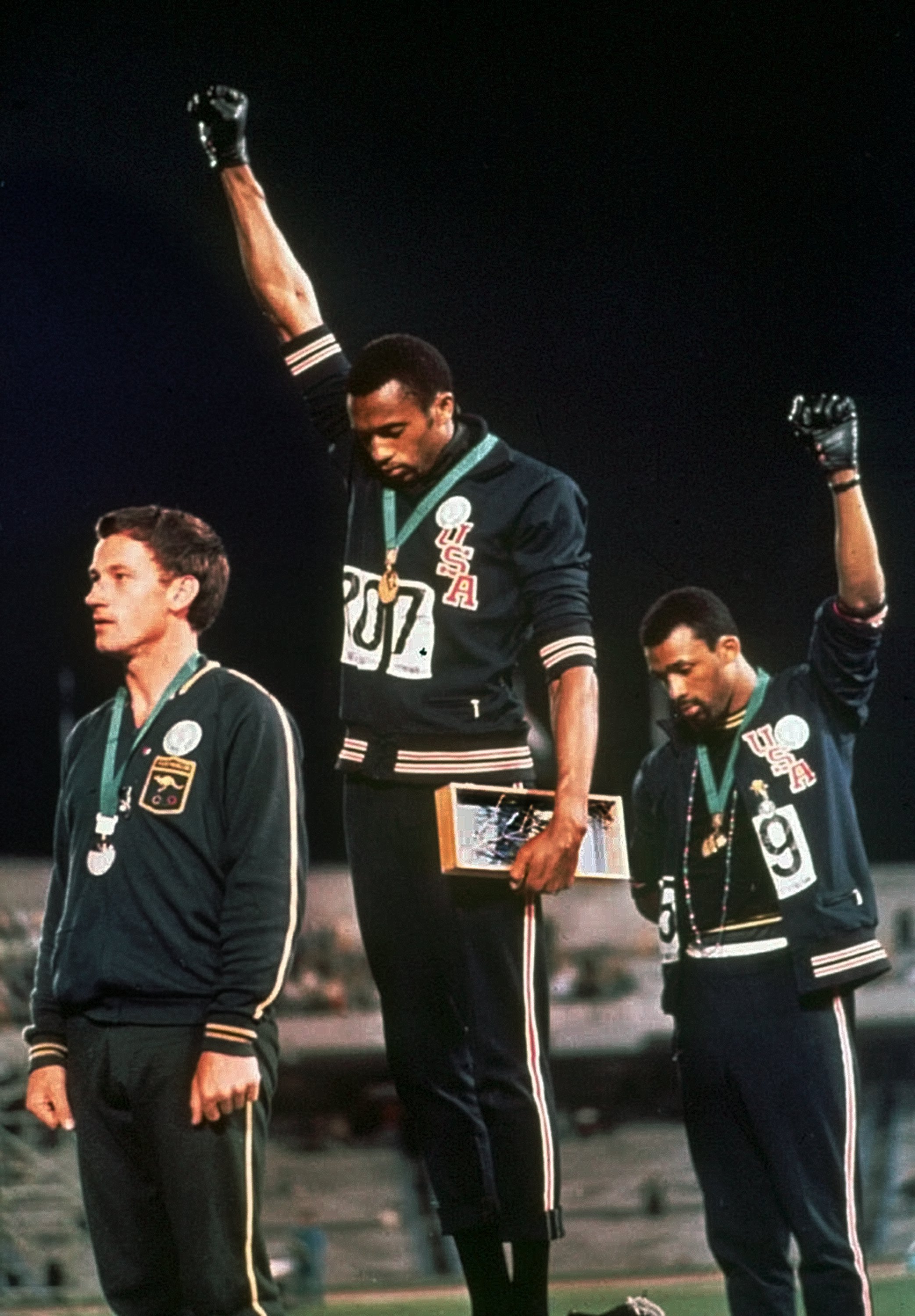 Extending gloved hands skyward in racial protest, U.S. athletes Tommie Smith, center, and John Carlos stare downward during the playing of the Star Spangled Banner after Smith received the gold and Carlos the bronze for the 200 meter run at the Summer Olympic Games in Mexico City on Oct. 16, 1968. Australian silver medalist Peter Norman is at left. (AP Photo)