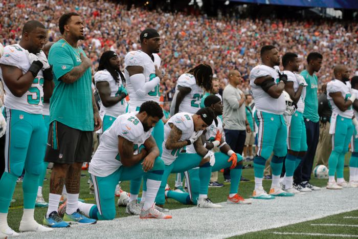 Miami Dolphins Arian Foster (29), Kenny Stills (10) and Michael Thomas (31) kneel during the national anthem before an NFL football game against the New England Patriots Sunday, Sept. 18, 2016, in Foxborough, Mass. (AP Photo/Steven Senne)