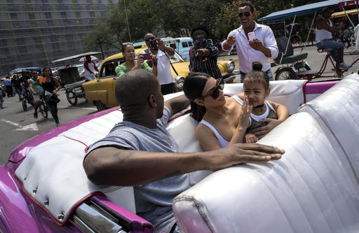 American reality-show star Kim Kardashian wipes her daughter's face, North West, as she rides in a classic American car with her husband, rap singer Kanye West in Havana, Cuba, Thursday, May 5, 2016. West, Kardashian and members of her reality-show-star family have become the latest celebrities to visit Havana. (AP Photo/Ramon Espinosa)