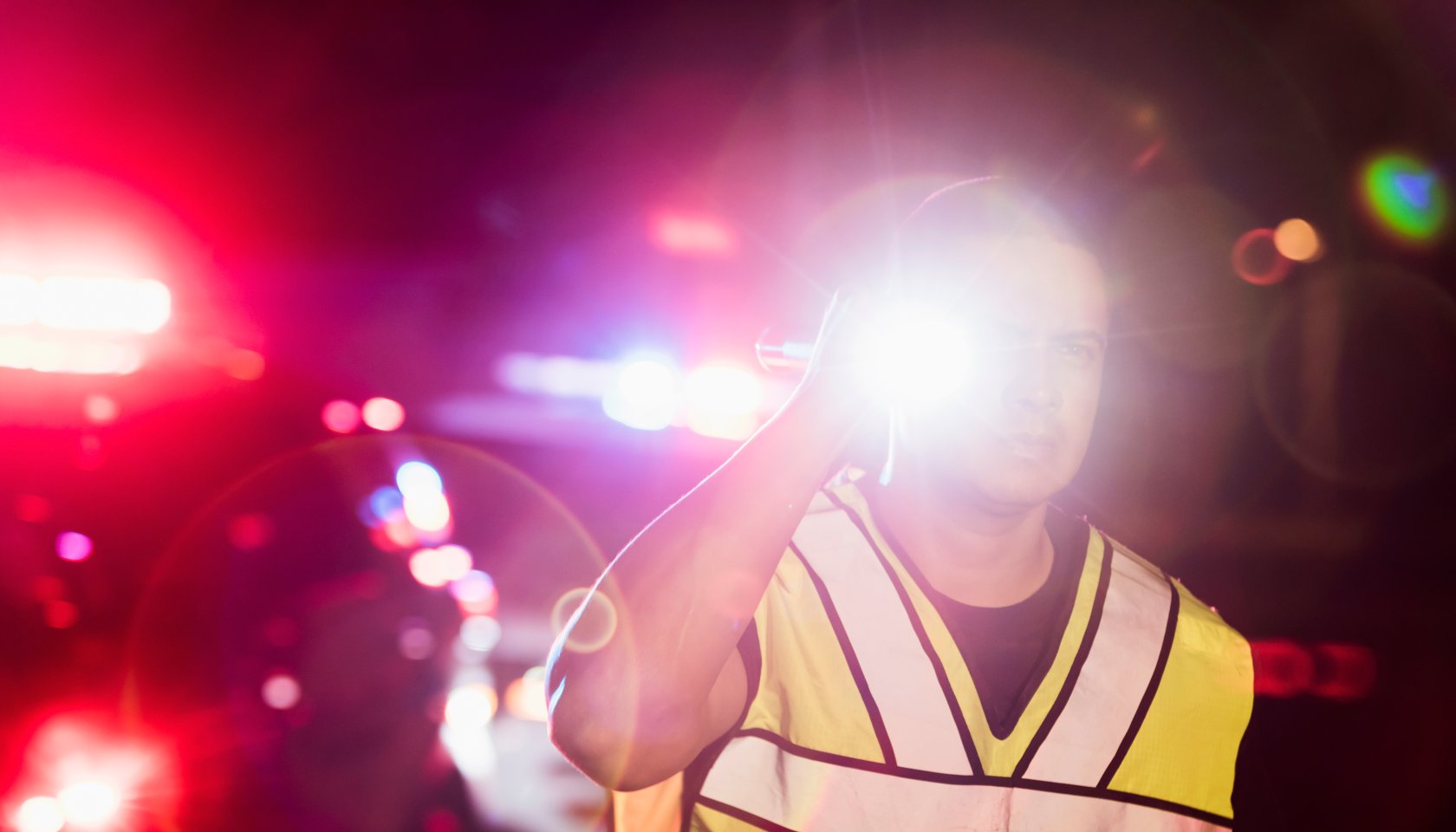 Hispanic police officer at night, flashing lights