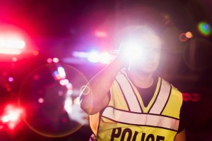 Hispanic police officer at night, flashing lights