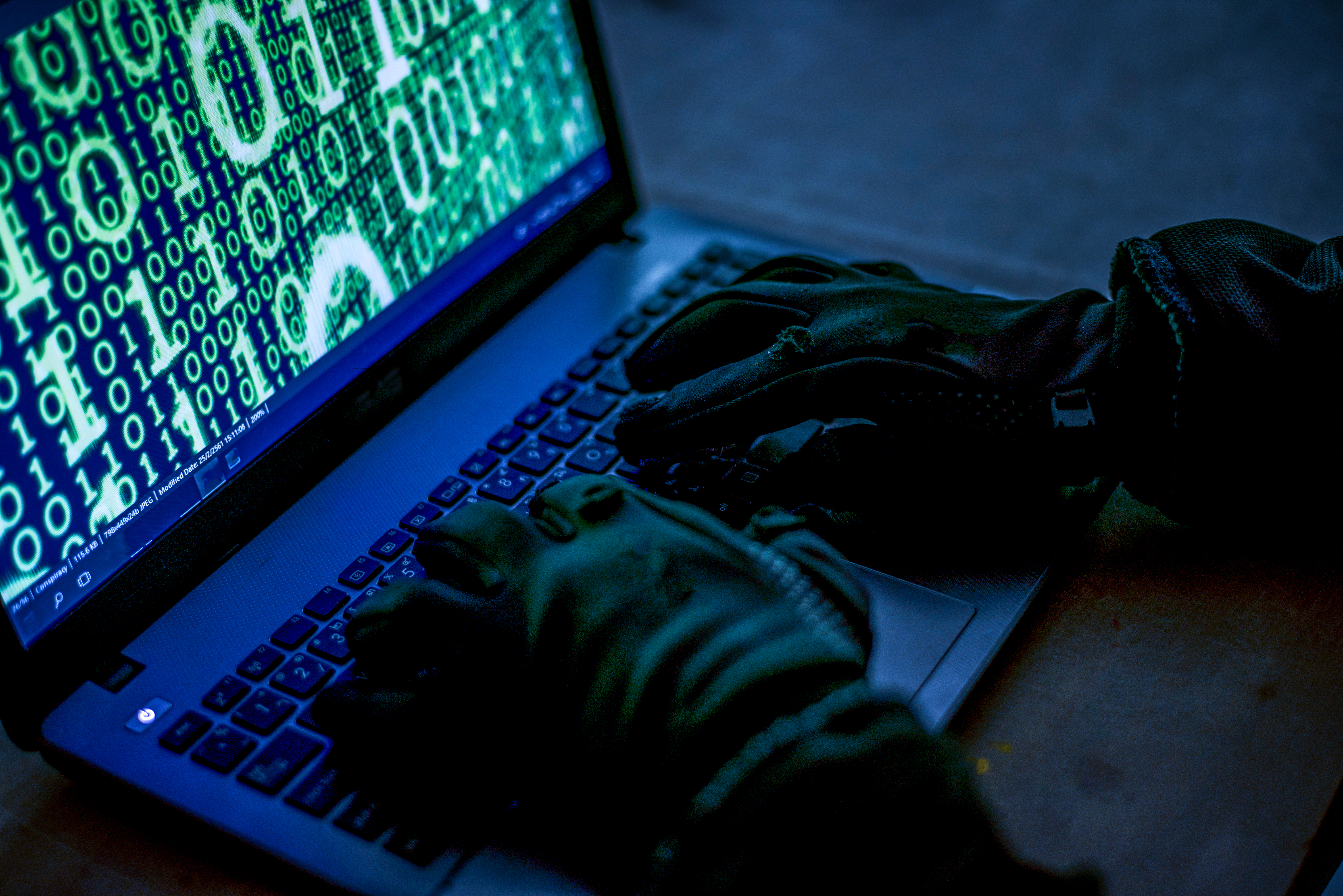 Hacker using laptop. Lots of digits on the computer screen.