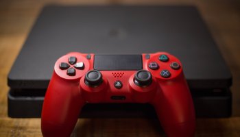 A Sony PlayStation 4 video game console with a red wireless...