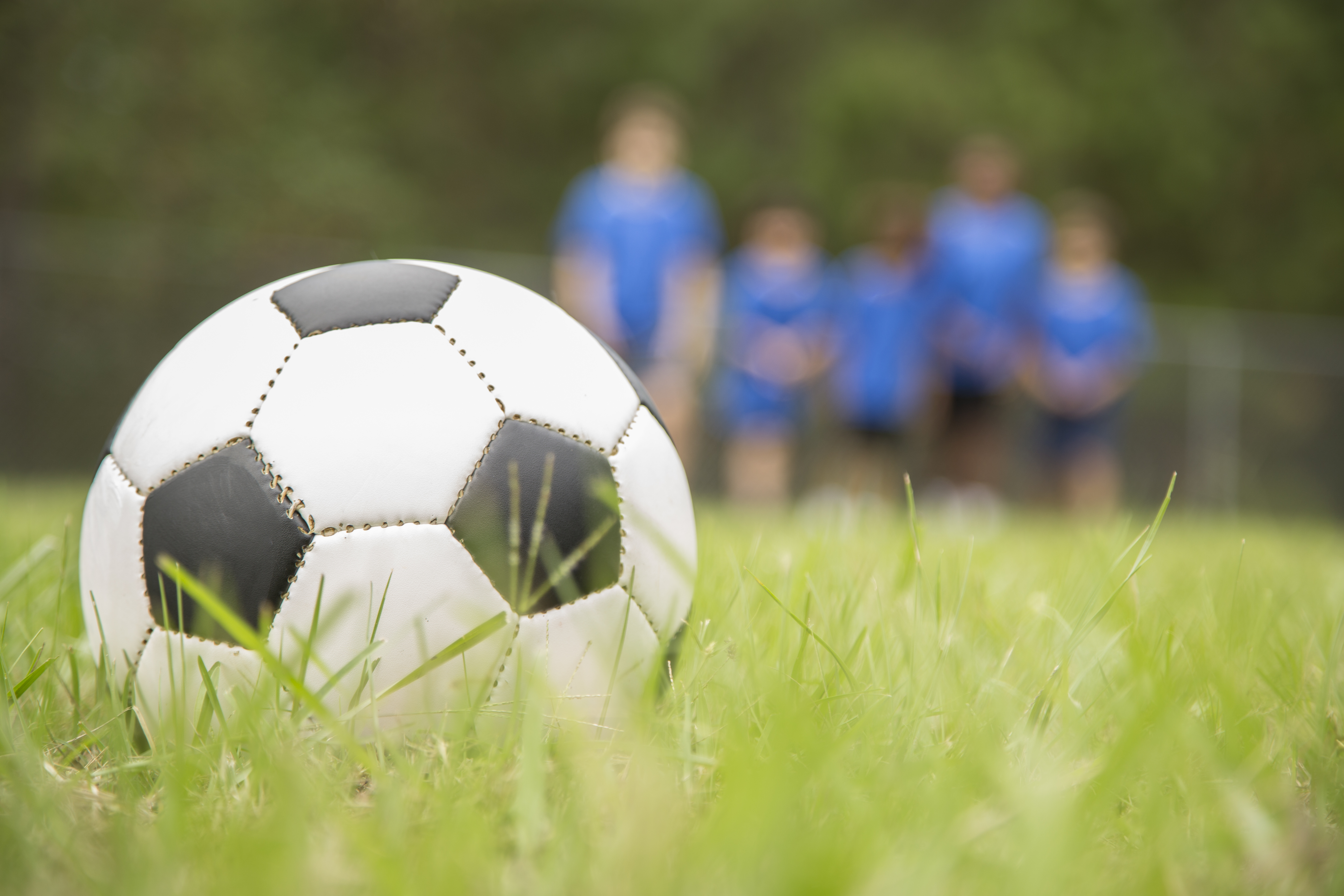 Children's soccer team players run toward ball on playing field.
