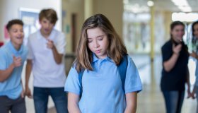Sad teen female being bullied in hallway