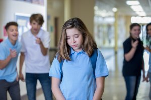 Sad teen female being bullied in hallway