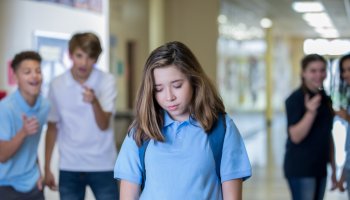 Sad teen female being bullied in hallway