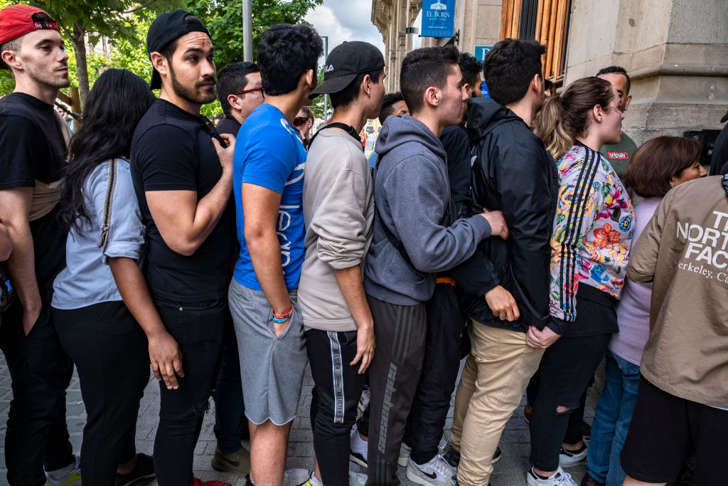 A group of young people stand in a queue to access the...