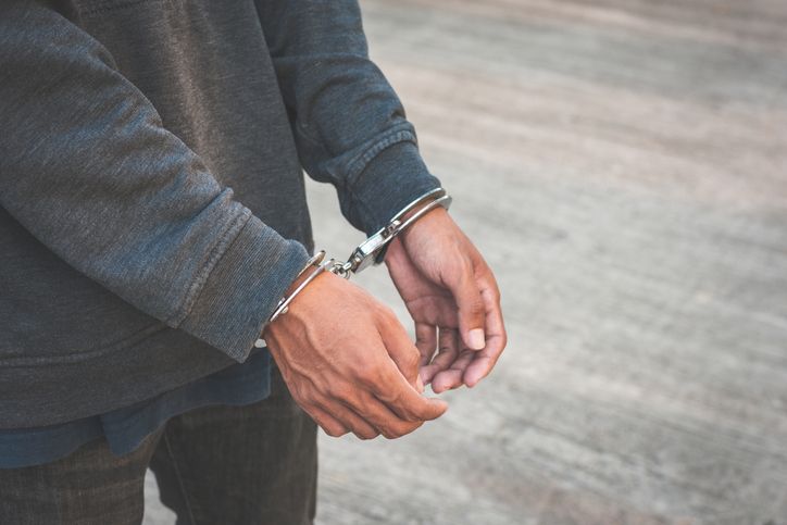 Arrested businessman handcuffed hands. Close-up.