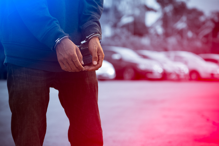 Cropped Hands Of Handcuffs Over red and blue lights Background