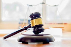 Close-Up Of Gavel And Weight Scale On Table In Courtroom