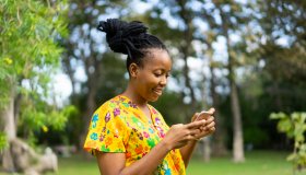 Beautiful african female feeling happy and use smartphone or cellphone with Green background and bokeh