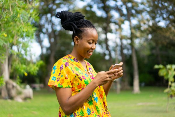 Beautiful african female feeling happy and use smartphone or cellphone with Green background and bokeh