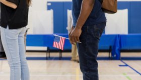 Unrecognizable man holds US flag while waiting to vote