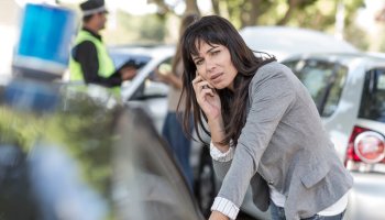Woman on cell phone at car accident scene