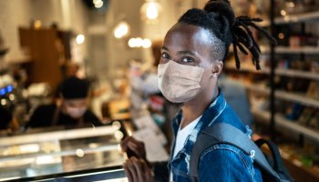 Portrait of young customer with face mask in coffee shop