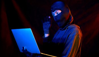 Computer hacker stealing information with laptop