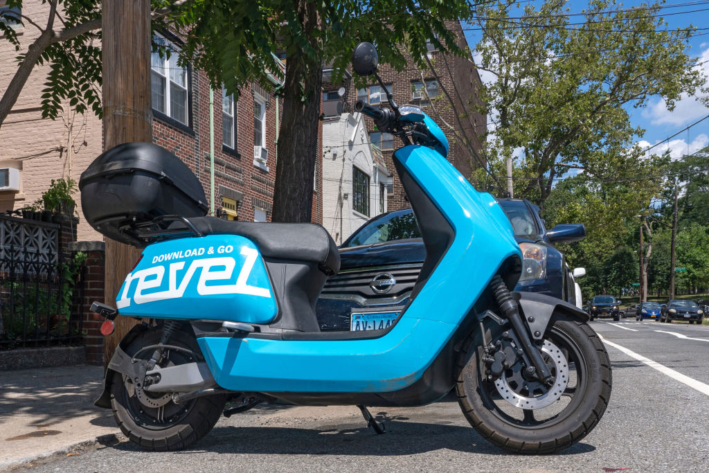 A Revel moped is parked unused on the street in the Queens...