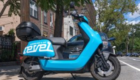 A Revel moped is parked unused on the street in the Queens...