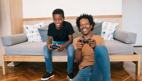 Father With Son Playing Video Game At Home