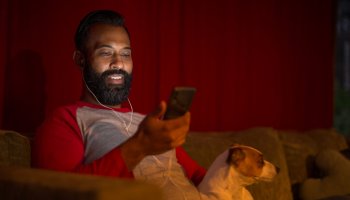Mixed race man looking at smart phone at home during lockdown