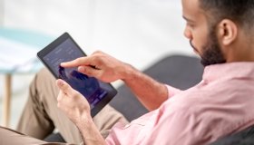 Mixed race man using a digital tablet to check cryptocurrency graphs