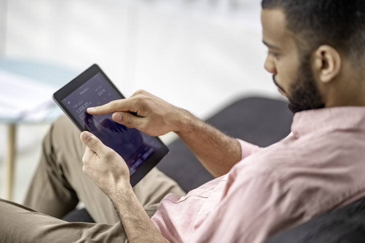 Mixed race man using a digital tablet to check cryptocurrency graphs