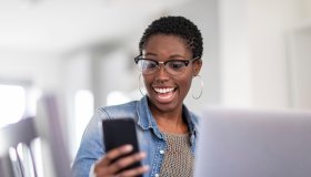 Smiling woman looking at smart phone at home