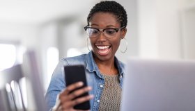 Smiling woman looking at smart phone at home