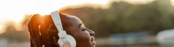 Young African American woman outdoors on sunset and listening music