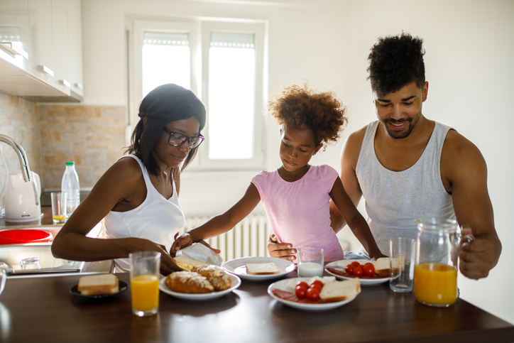 Young happy African American family having breakfast at home