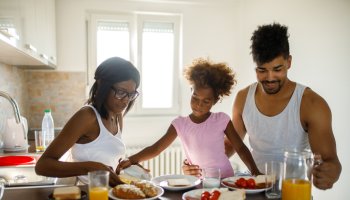 Young happy African American family having breakfast at home