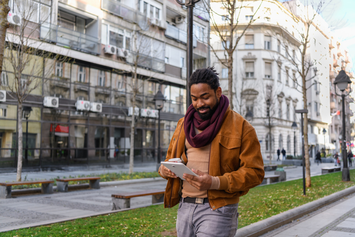 Portrait of a Handsome African Man with Coffee Walking in the City Streets, Using a Digital Tablet.