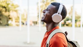 Happy man with closed eyes laughing in the street while listening to music