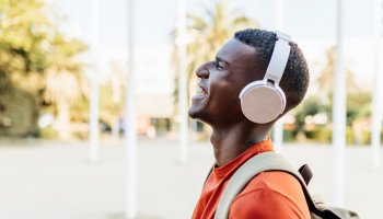 Happy man with closed eyes laughing in the street while listening to music