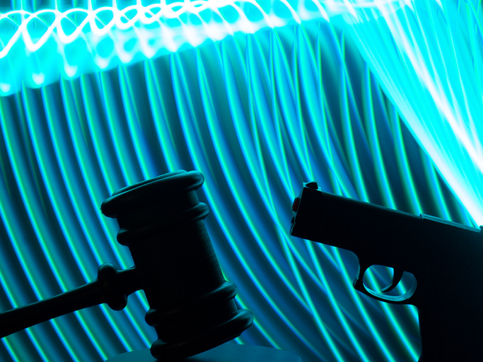 Silhouette of a guns and a Judge's gavel with curved blue lines in the background.