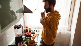 Young man drinking healthy smoothie in the kitchen at home