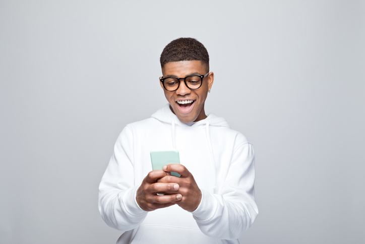 Portrait of surprised young man using smart phone