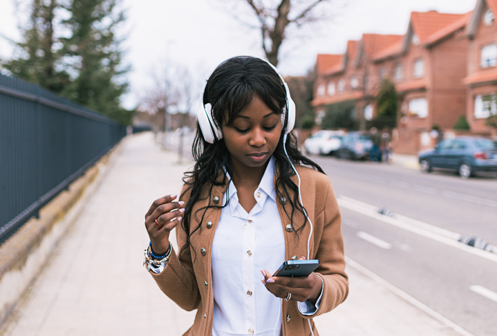 Gadis multirasial mendengarkan musik dan SMS di jalan, Wanita mengirim pesan dan mendengarkan musik di jalan, Konsep gaya hidup wanita di jalan