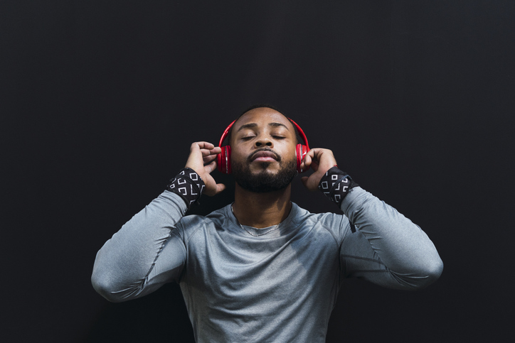 Athete with eyes closed listening music on headphones against black background