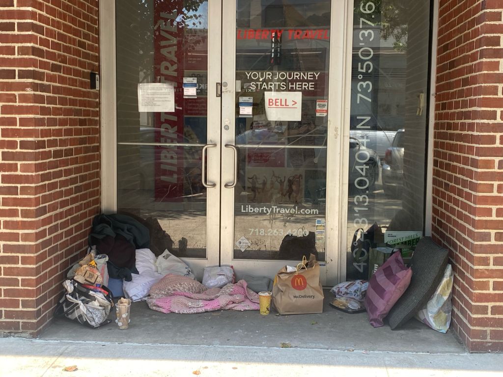 Homeless encampment in doorway of closed business, post pandemic city life, Queens, New York