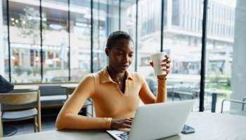 Young african woman freelancer working on laptop while sitting in coworking