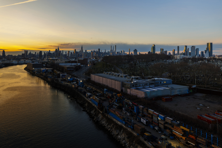 Urban skyline and Newtown Creek with industrial area on the right bank at sunset cloudy sky background. The view from Kosciuszko Bridge