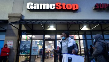 A man wearing a face mask leaves Game Stop with the new...