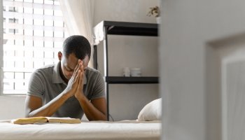 Adult man with hands together making a pray indoor at home. belief concept.