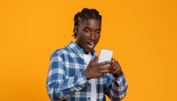 Great App. Amazed young black man looking at smartphone screen with excitement