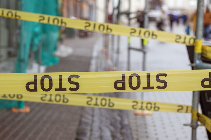 .Yellow warning tape with the inscription "STOP" delimiting access to a certain area, possibly due to construction work.