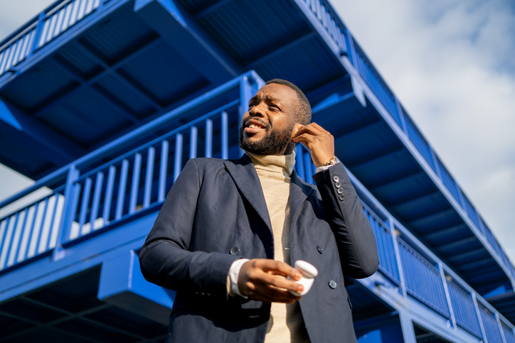 African businessman putting on earbuds in the street