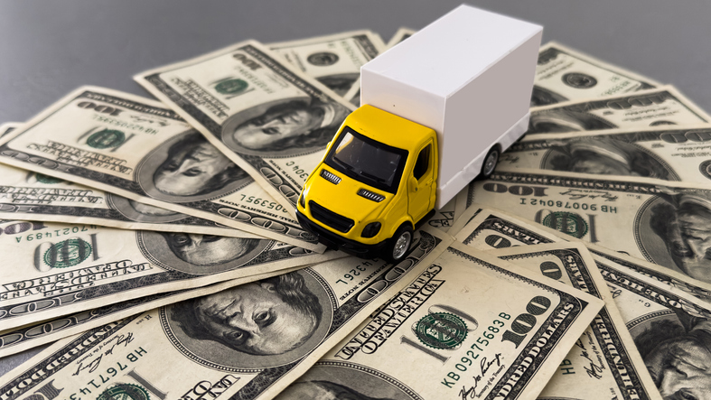 Delivery truck on hundred dollar bills banknotes. Background of moving or trucking concept close up